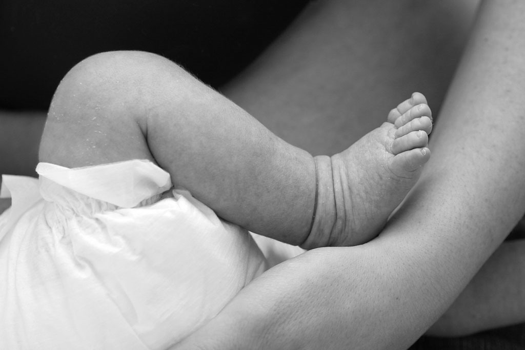 Babyfuß auf dem Arm der Mutter